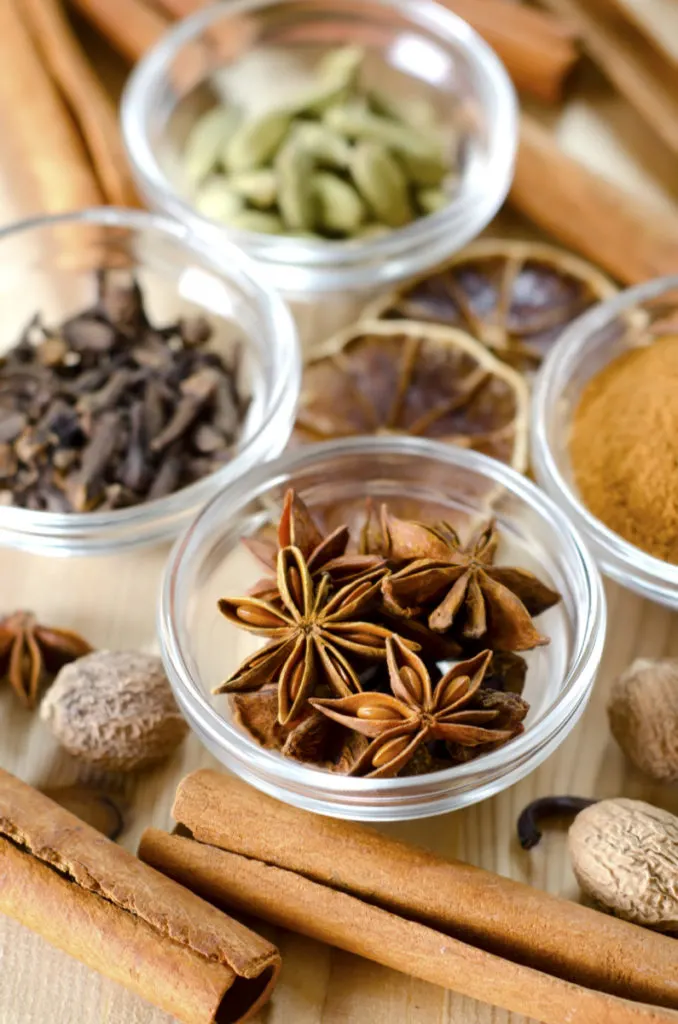 Aromatic spices like cloves, cinnamon sticks, and whole nutmeg on a wooden table. 