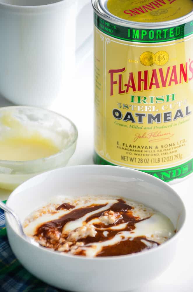 A bowl of steel cut oats topped with a brown sugar cinnamon glaze and cream cheese swirl topping, next to a canister of Flahavan's Irish Steel Cut Oats. 