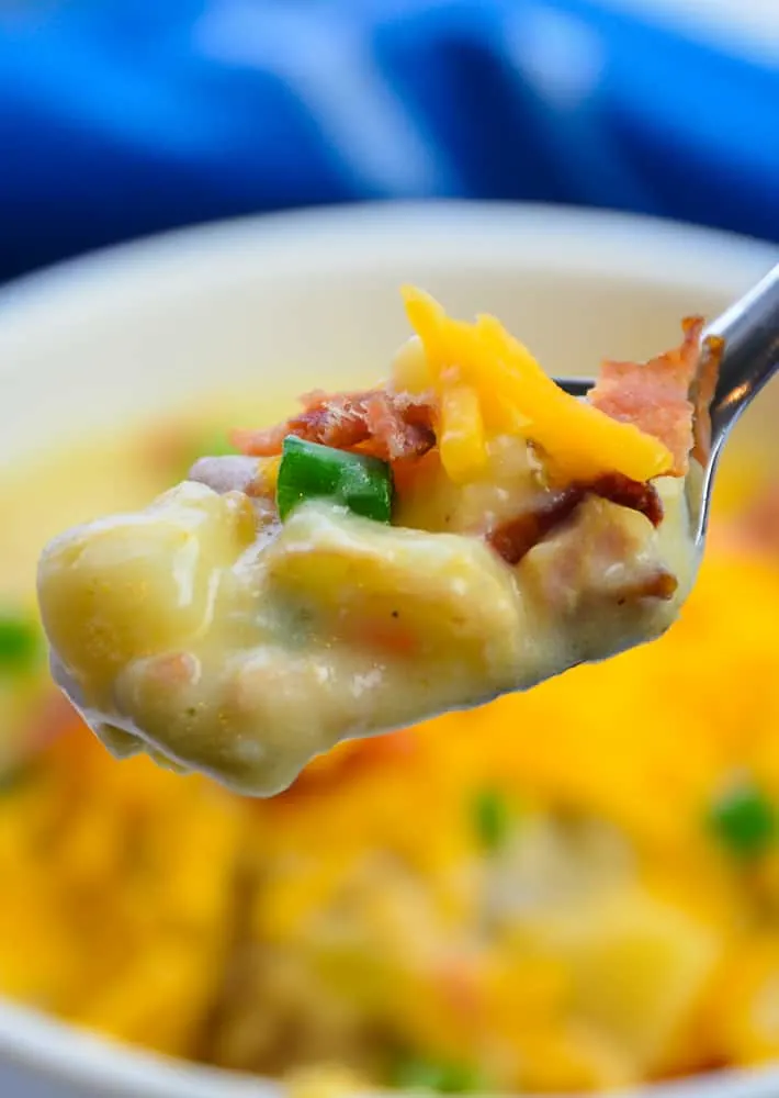 Spoonful of Loaded Baked Potato with heary baked potatos chunks, in a creamy soup