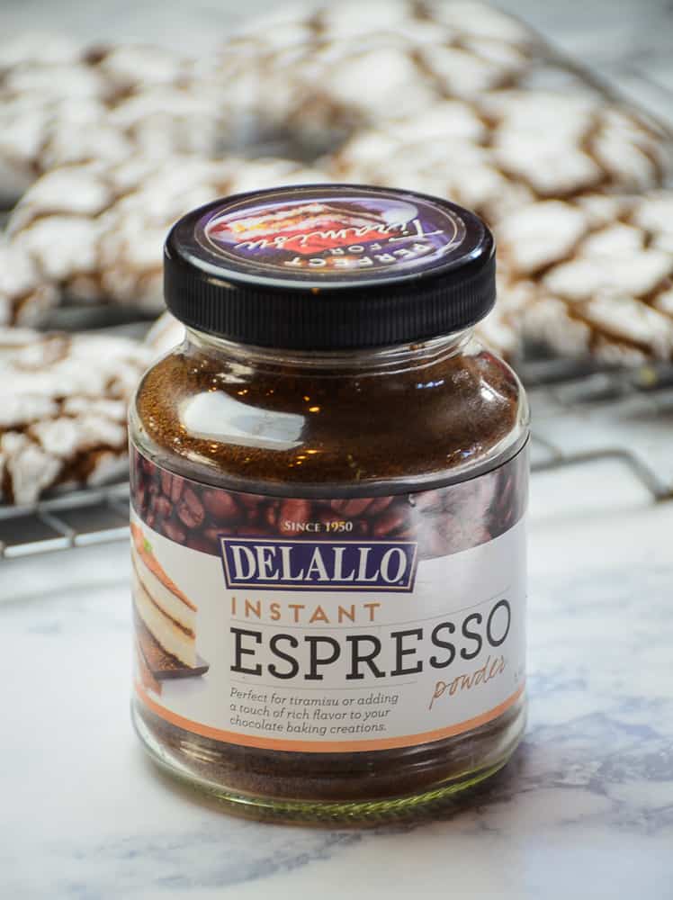 Jar of Delallo Espresso powder with Chocolate Crinkle Cookies in the background. 